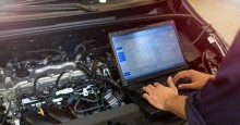 Mechanic with computer checks vehicle.